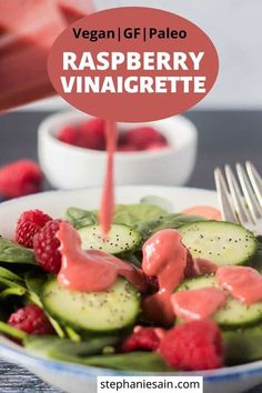 raspberry vinaigrette dressing being poured onto a plate with cucumbers and raspberries