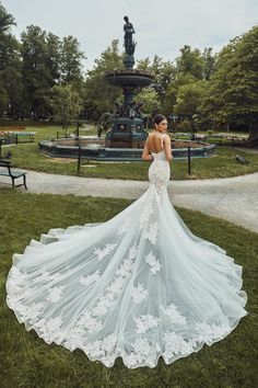 a woman in a wedding dress standing on the grass with her back to the camera