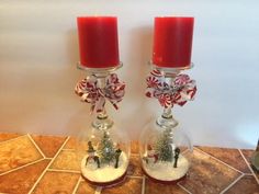 two red candles sitting on top of a counter next to snow globes with christmas decorations