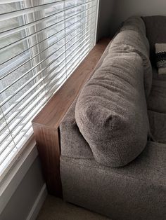 a couch sitting in front of a window with blinds on it's windowsill