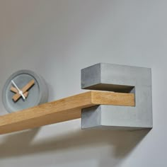 a clock mounted to the side of a wall next to a wooden beam with a piece of wood sticking out of it