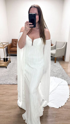 a woman taking a selfie with her cell phone in a white dress on the floor