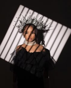 a woman with a crown on her head standing in front of a white and black wall