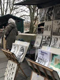 an old woman is looking at posters for sale