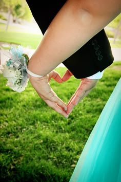 the bride and groom hold hands in front of their heart shaped wedding bouquet on green grass