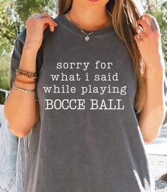 "Sorry for What I Said While Playing Bocce Ball Shirt, (Text Only - No Bocce Image), Comfort Colors T-shirt, Bocce Ball Yard Game Tshirt No worries about apologizing for expletives or competitive banter during future bocce ball games - this shirt speaks for you! Check out the \"Sorry for What I Said While Playing Bocce Ball\" t-shirt. It's a great gift idea for the bocce ball lover in your life, or get one for yourself to wear to your next bocce ball family game days or to your next bocce tournament.  Designed on the premium canvas of the much-loved Comfort Colors garment-dyed t-shirt; made 100% with ring-spun US cotton. This t-shirt particular design is available on 4 t-shirt colors: pristine White for a fresh look, elegant Ivory for a soft and timeless appeal, earthy Moss to connect with Ball Family, Yard Game, Ball Image, Bocce Ball, Ball Games, Balls Shirt, Team Shirts, Branded Shirts, Dye T Shirt