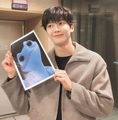 a young man holding up a poster with an image of a blue dog on it