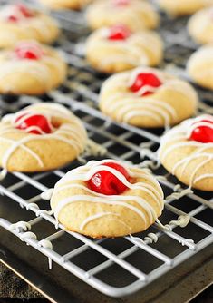 cookies with white icing and cherries on a cooling rack