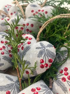 some red berries and green branches are on white fabric wrapped in burlocks with twine