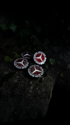 three red and white buttons sitting on top of a rock in the woods at night