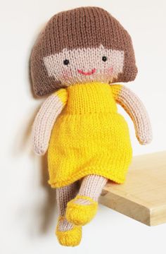 a knitted doll sitting on top of a wooden shelf next to a white wall