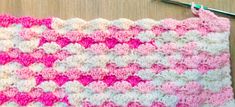 a crocheted pink and white blanket next to a pair of scissors