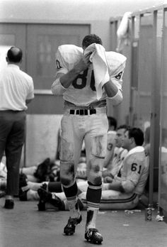 an old black and white photo of a football player wiping his face with a towel