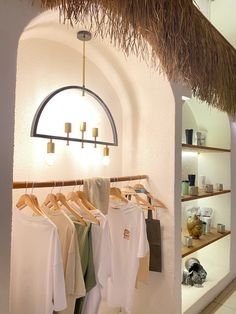 clothes hanging on racks in front of a hut with thatched roof and lights above it