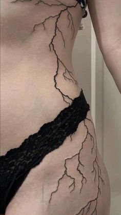 a woman's stomach with black lace on it, and lightning bolt tattoo on the side