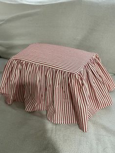 a red and white striped bed skirt sitting on top of a couch next to a pillow