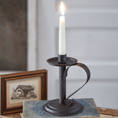 a lit candle sitting on top of an old book next to a picture and framed picture