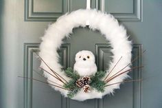 a white wreath with an owl and pine cones