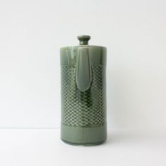 a green vase sitting on top of a white table