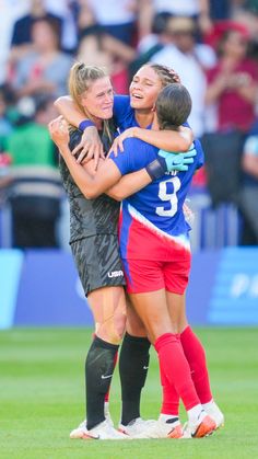 two female soccer players hugging each other on the field