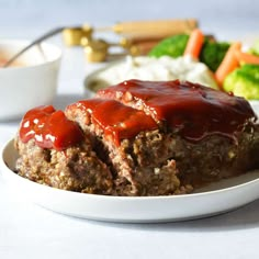 meatloaf covered in ketchup on a white plate with salad and dressing