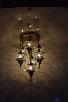 a chandelier hanging from the ceiling in a dark room with lights on it