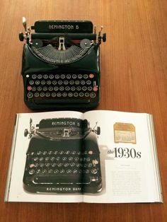 an old fashioned black typewriter sitting on top of a table next to a book