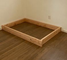 a bed frame sitting on top of a hard wood floor next to a white wall