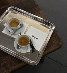 two cups of coffee sitting on top of a wooden table