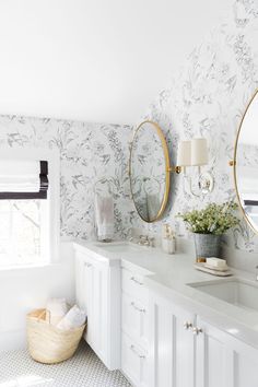 a bathroom with two sinks, mirrors and flowers on the wall in front of it