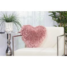 a heart shaped pillow sitting on top of a white couch next to a potted plant