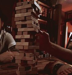 two men sitting at a table with stacks of wooden blocks on top of each other