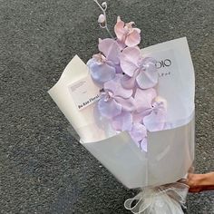 a person holding a bouquet of flowers on the ground in front of a bag that is wrapped in plastic