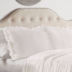 a bed with white sheets and pillows on it