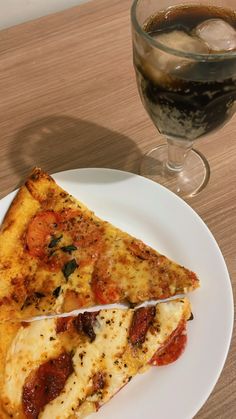 two slices of pizza sitting on top of a white plate next to a glass of wine