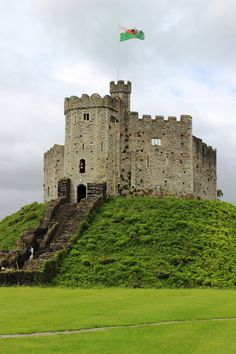 an old castle with stairs leading up to it and a flag flying on the top