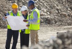 three people in hard hats and safety vests looking at a blueprint