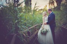 a bride and groom standing on a bridge in the woods