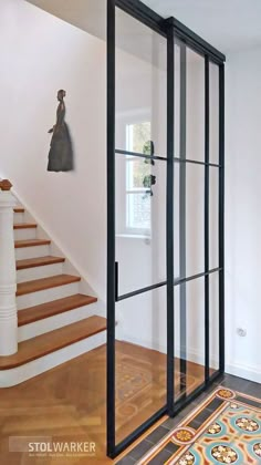 an open glass door in the middle of a room with wooden floors and white walls