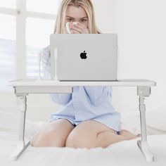 a woman is sitting on the bed with her laptop in front of her and looking at the screen