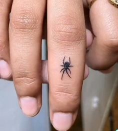 a person with a small spider tattoo on their finger