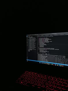 a computer screen with red lights shining on it's side and keyboard in the foreground