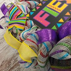 a colorful wreath with ribbons and a sign on it