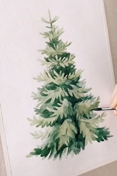 someone is painting a christmas tree with watercolors