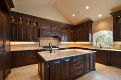 a large kitchen with brown cabinets and marble counter tops