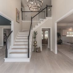 an open floor plan with stairs and chandelier