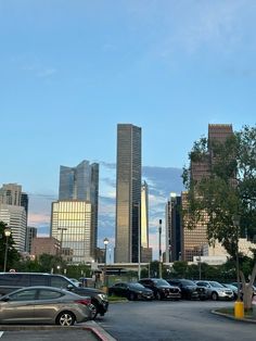 cars are parked in a parking lot with skyscrapers in the background