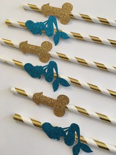 blue and gold mermaid party straws with glitter bows on them are lined up in a row