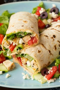 two wraps with chicken, lettuce, tomatoes and cucumber on a blue plate