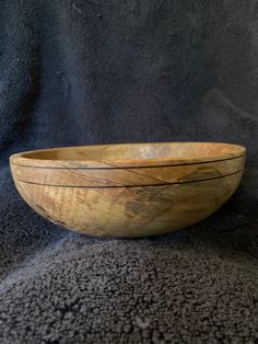 a wooden bowl sitting on top of a black cloth